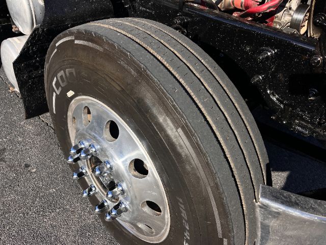 Wheel and tire assembly of a 2013 Mack CHU613 Pinnacle show large dual-line tread tire with chrome lug nuts and aluminum wheel, part of a conventional daycab.