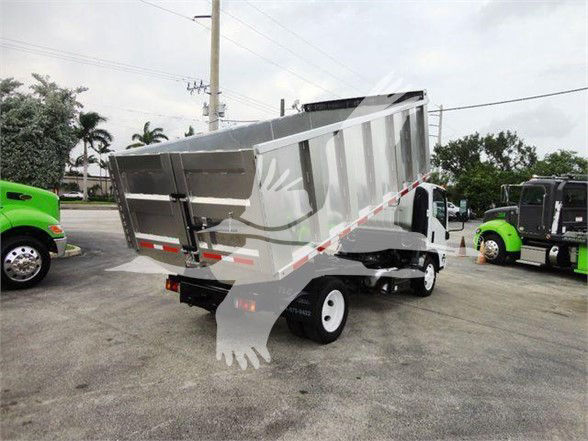 Isuzu NQR dump truck with aluminum dump bed in a dealership lot, rear view showing hydraulic lift and dual rear wheels.
