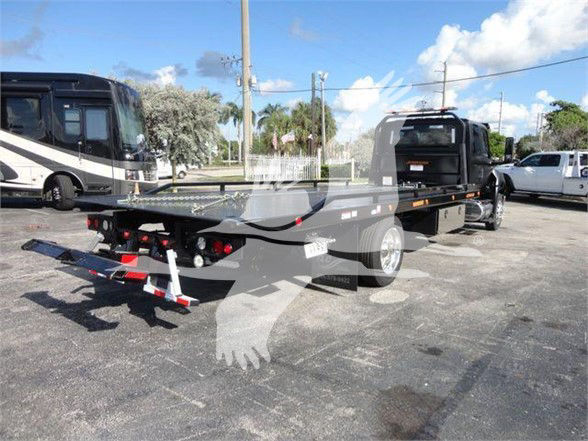 2023 International MV tow truck flatbed with trailer, rear view showing winch and daylight background.