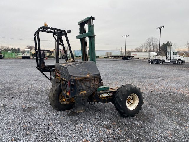 Kesmac F5000 truck-mounted forklift in a gravel lot showing operator cage and vertical mast.