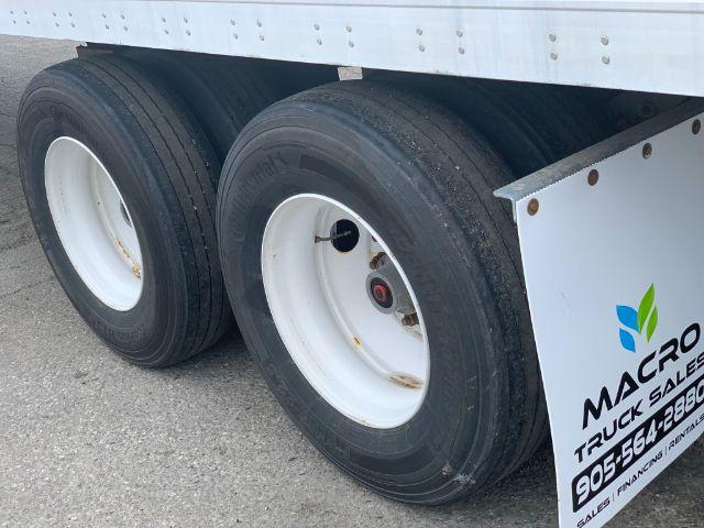 Manac dry van trailer wheel area showing dual axles with black tires and white rims, side panel and fender.