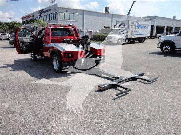 2024 Ram 4500 SLT tow truck with front doors open and a tow fork attachment on the ground in a dealership lot.