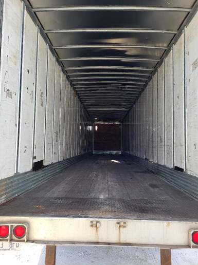 Utility trailer interior showing empty cargo area with metal side walls and open rear hatch.