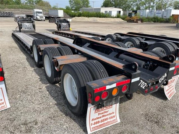 Lowboy trailer showing triple-axle rear with Magnitude branding under a pony motor, 2020 Fontaine 55TON Tri-Axle Lowboy. Visible: tires, metal frame, rear lighting, license plate holders.