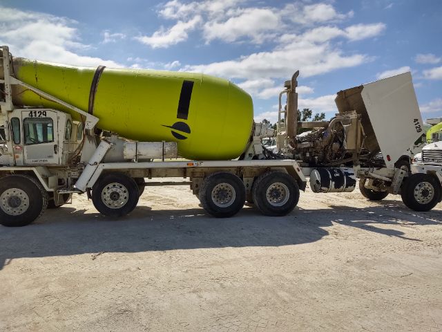 Terex mixer truck with bright lime green cement mixer drum attached to a multi-axle trailer; vehicle numbers visible on the cab”, showing the cement mixer and loading components.
