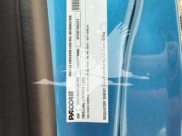 Vehicle emission control information label on a blue Kenworth T880 door jamb showing EPA compliance and engine family details.