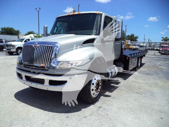 International MV tow truck front-left view showing chrome grille, headlights, and flatbed with dual rear wheels.