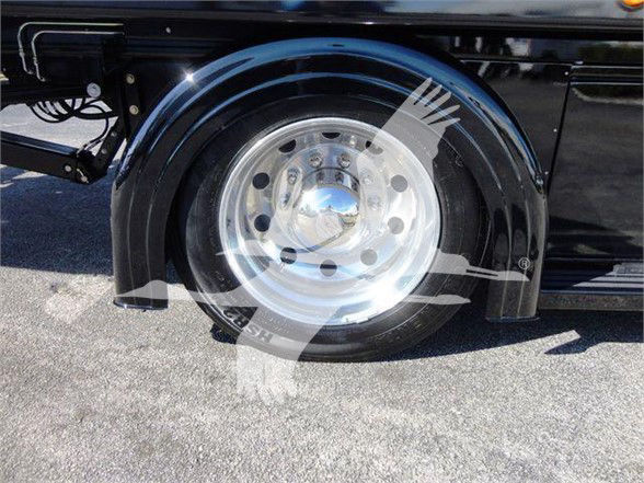 Wheel well and chrome hubcap of a black 2022 International MV truck showing polished aluminum wheel and fender; partial vehicle undercarriage visible.