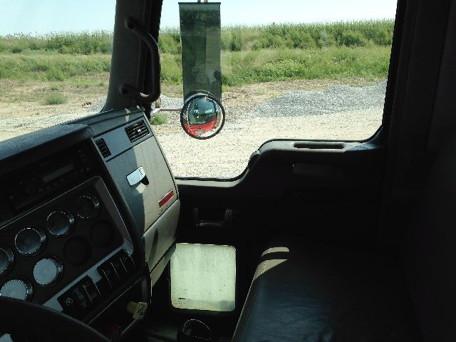 Dashboard and windshield of a Kenworth truck cab with circular gauges and side window, interior view.