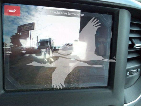 Ram 4500 SLT vehicle dashboard display showing backup camera view with a bird watermark overlay and reflections of trucks outside.