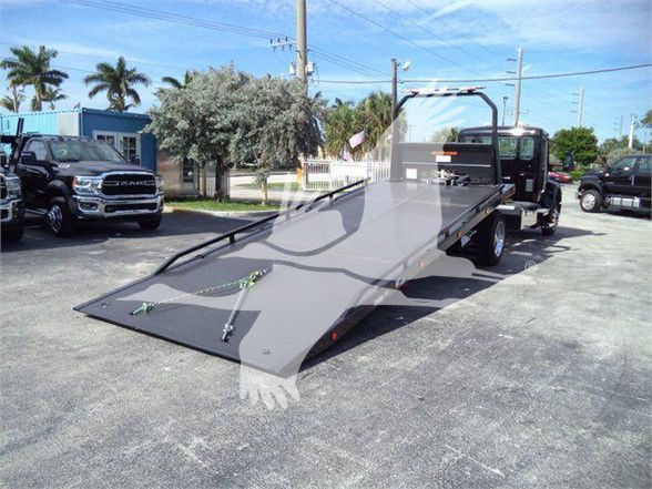 Kenworth T280 tow truck with a lowered flatbed; front cab visible with lot of text not legible on side.