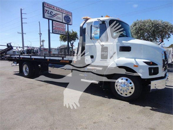 Flatbed tow truck image showing a white 2024 Mack MD6 with a long wheelbase and chrome wheels, signage in background, stock number WHTMACKMD6.