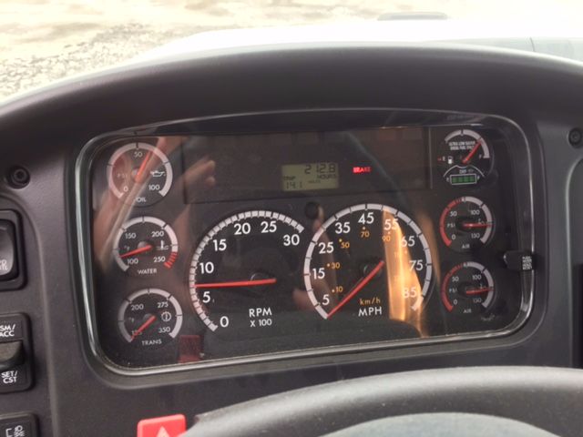 Dashboard of a Freightliner 108SD showing analog gauges including RPM x100, speedo, and multiple smaller gauges with a digital display in the center.