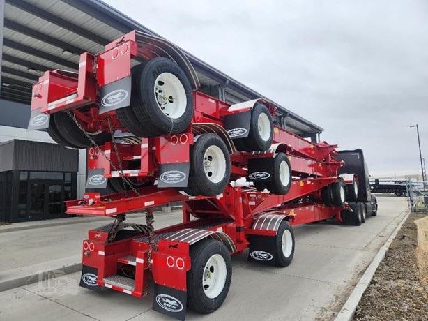 Chassis trailer stack with bright red frame and multiple white wheels, black tires, and a black cab visible in distance.