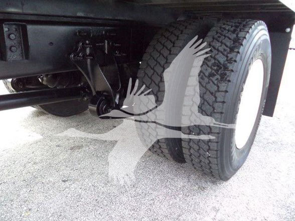 Wheel and undercarriage of a box truck showing dual rear tires and suspension components.