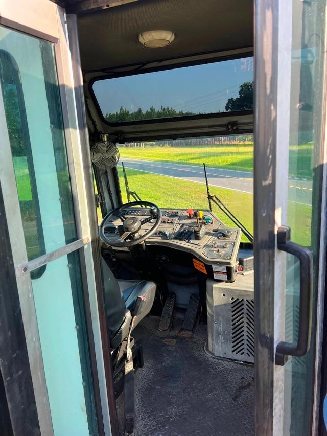 Operator cab of a 2015 Tico Prospotter with steering wheel, control panel, and pedals visible inside the enclosed cab.