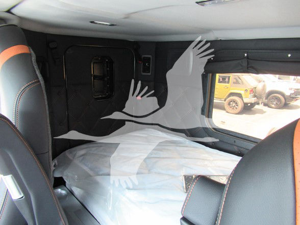 Kenworth W990 truck interior cargo area with sleeper cabin, visible window, and protective coverings.