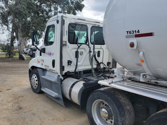 Freightliner Cascadia truck tractor with concrete mixer trailer attached, side view showing cab door, steps, and hoses.