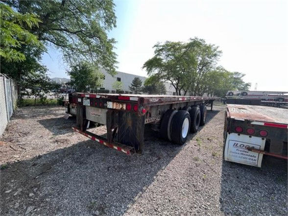 Manac 2014 flatbed trailer showing rear end with triple axles and reflective tape.