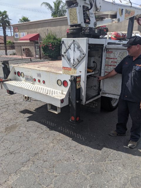 Platform truck with aerial lift on white service body showing control panel and warning labels.
