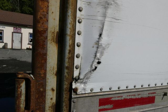 Fruehauf trailer rear corner with riveted aluminum side and rusted steel frame showing wear.