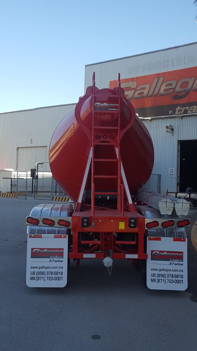 Rear view of a bright red Gallegos pneumatic trailer with a large cylindrical tank and a ladder, brand name Gallegos visible, trailer mudflaps with Gallegos logos, in a warehouse area.