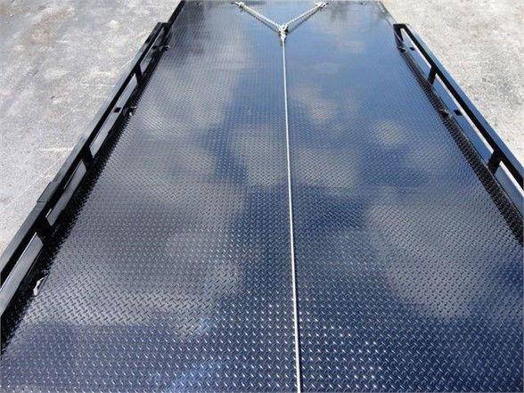 Flatbed truck rear view with diamond plate metal surface, center seam and ramps on both sides.