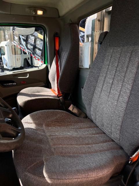 Peterbilt 579 interior showing driver seat and passenger bench with gray fabric upholstery and orange seat belt.