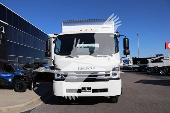 Isuzu FTR box truck front view with white cab, Isuzu logo on grille, and dealership lot in background.