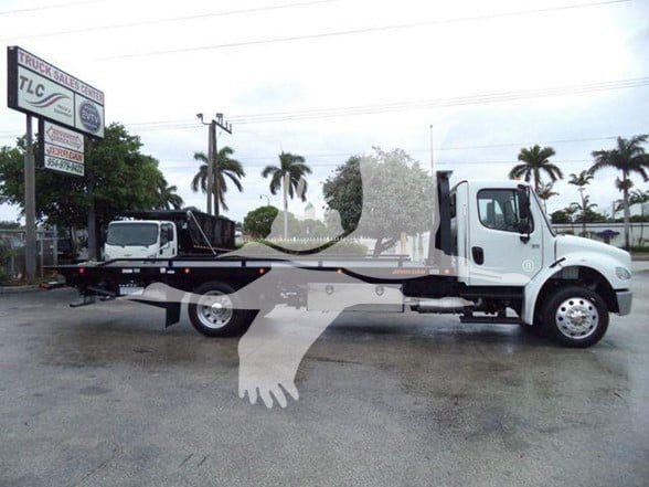 Truck side view showing a white Freightliner Business Class M2 106 tow truck with a flatbed and hydraulic winch.