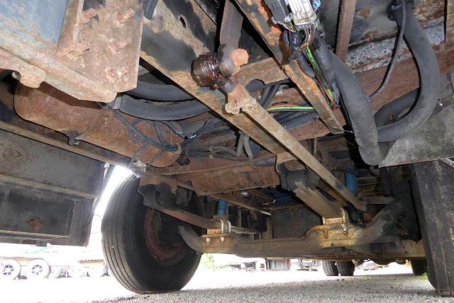 Underbody view of a 2005 Bluebird All American bus showing chassis, suspension, and drivetrain components with rust and wiring harnesses.