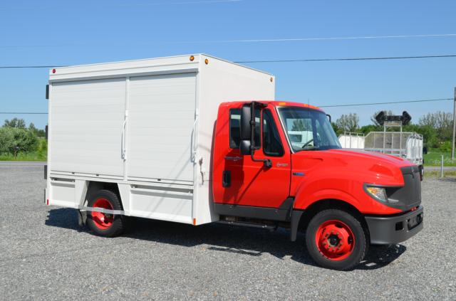 Utility truck with red cab and white box body. No text clearly visible on panels.