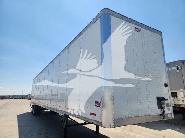 Wabash enclosed trailer in a yard, side and rear views visible with trailer legs and rear doors.