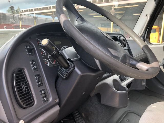 Cab interior of a 2007 Freightliner M2-112 showing steering wheel, dashboard, and gear selector.