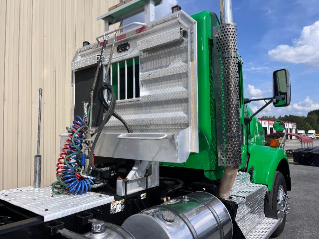 Kenworth T800 truck rear cab area with chrome exhaust stack and silver toolbox, green paint, and coiled air hoses.