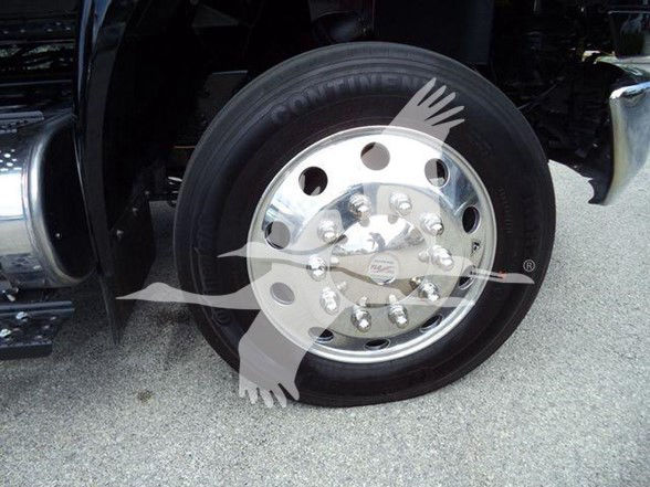 Truck wheel with polished chrome hub and lug nuts, tire visible, fender and surrounding areas of a tow truck in view.