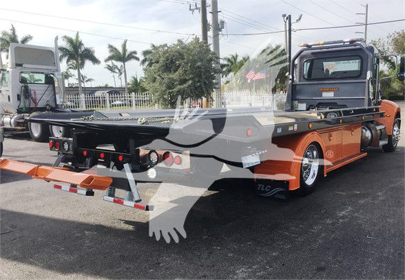 Tow truck chassis with flatbed in-service rear view. Visible text includes 'J47166' stock number on vehicle list and 'Peterbilt' branding on rear cab window.
