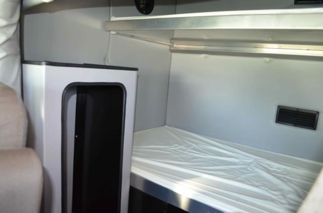 Truck sleeper cab interior with a metallic shelf and small cabinet in the foreground.