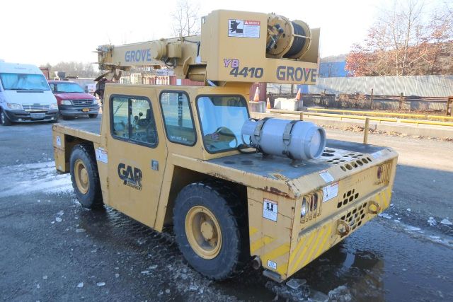 Grove YB4410 mobile crane on truck chassis with cab, showing yellow paint, crane arm labeled GLOVE? and 'YB 4410 GROVE' on boom; tires and rear counterweight visible.
