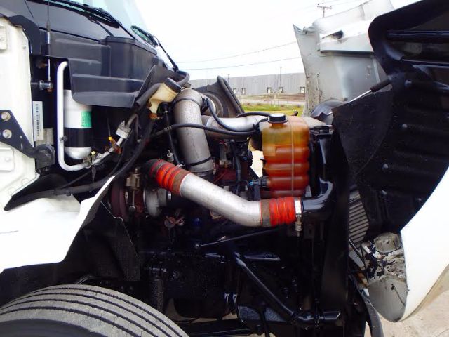 International 8600 truck engine bay showing turbo, intercooler piping, coolant reservoir, hoses, and front wheel well.