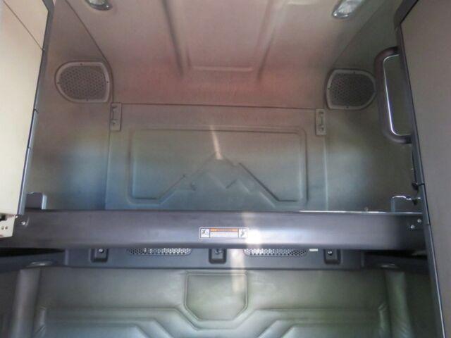 Freightliner Cascadia Evolution truck sleeper cab interior showing storage area and metal platform with textured floor; some vents and speakers visible.