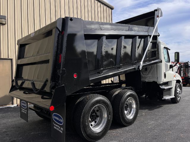 2019 Freightliner Cascadia 125 dump truck with black dump bed raised, white cab, dual rear axles. Wheel rims, side mirrors, and truck body visible.