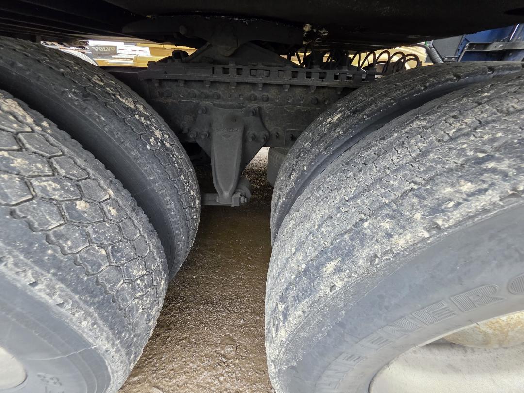 Dual rear axle wheels of a Freightliner Cascadia with muddy tires and visible suspension components.