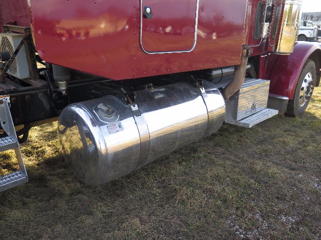 Peterbilt 388 truck tail with polished cylindrical fuel tank and side step showing undercarriage components.