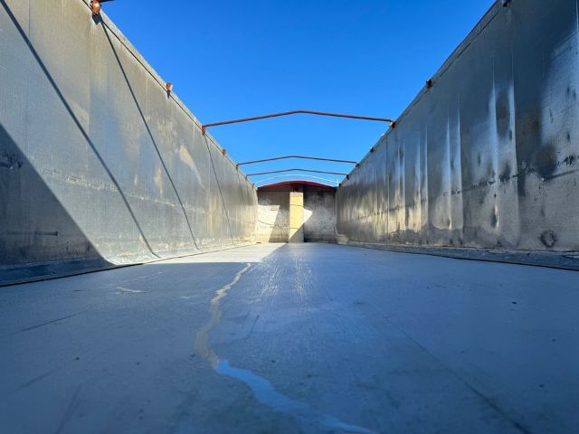 GMC trailer bed interior viewed from near floor, metal sides, empty ceiling overlay, blue sky visible.