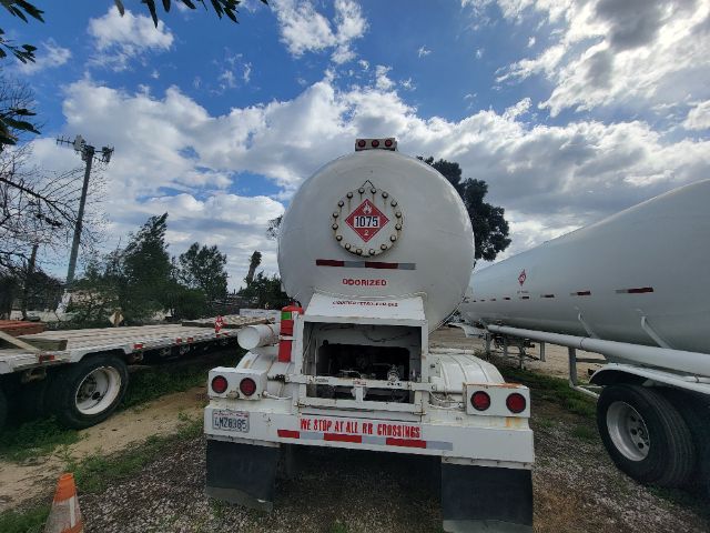 Rear view of a 2016 Freightliner Cascadia fuel tanker truck in a yard, showing the back of the tank, red hazard placard, and bumper with text.