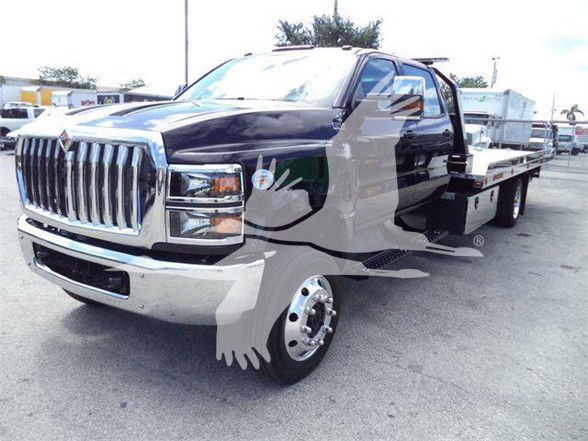 Front-left view of a 2023 International CV tow truck with a flatbed, chrome grille, and dual rear wheels.
