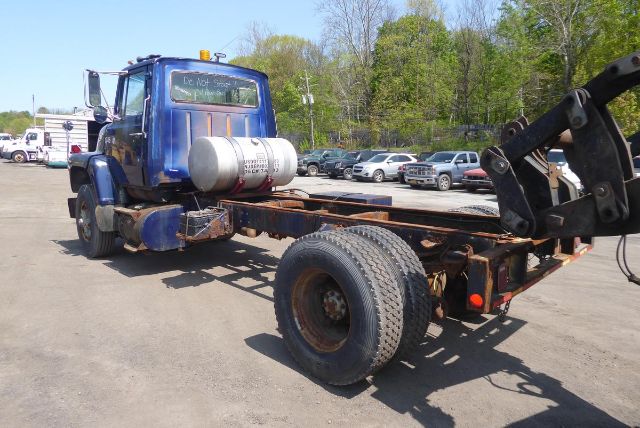 Ford 8000 cab and chassis truck with blue cab, exposed frame, and rear hydraulic setup. Tank attached to cab, spare tire, and equipment visible.