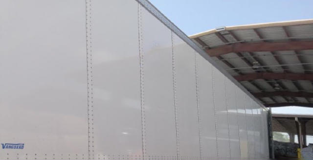 Vanguard trailer side with riveted metal panels and a small Vanguard logo near the bottom left.