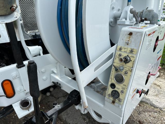 Peterbilt 340 vacuum truck equipment panel with hoses and control gauges visible.